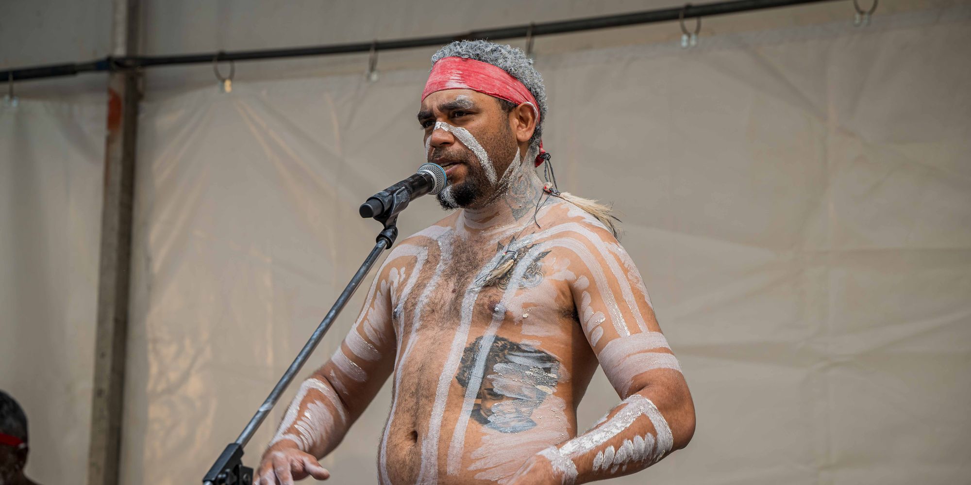Ryka Ali performing on stage with clapsticks at a microphone