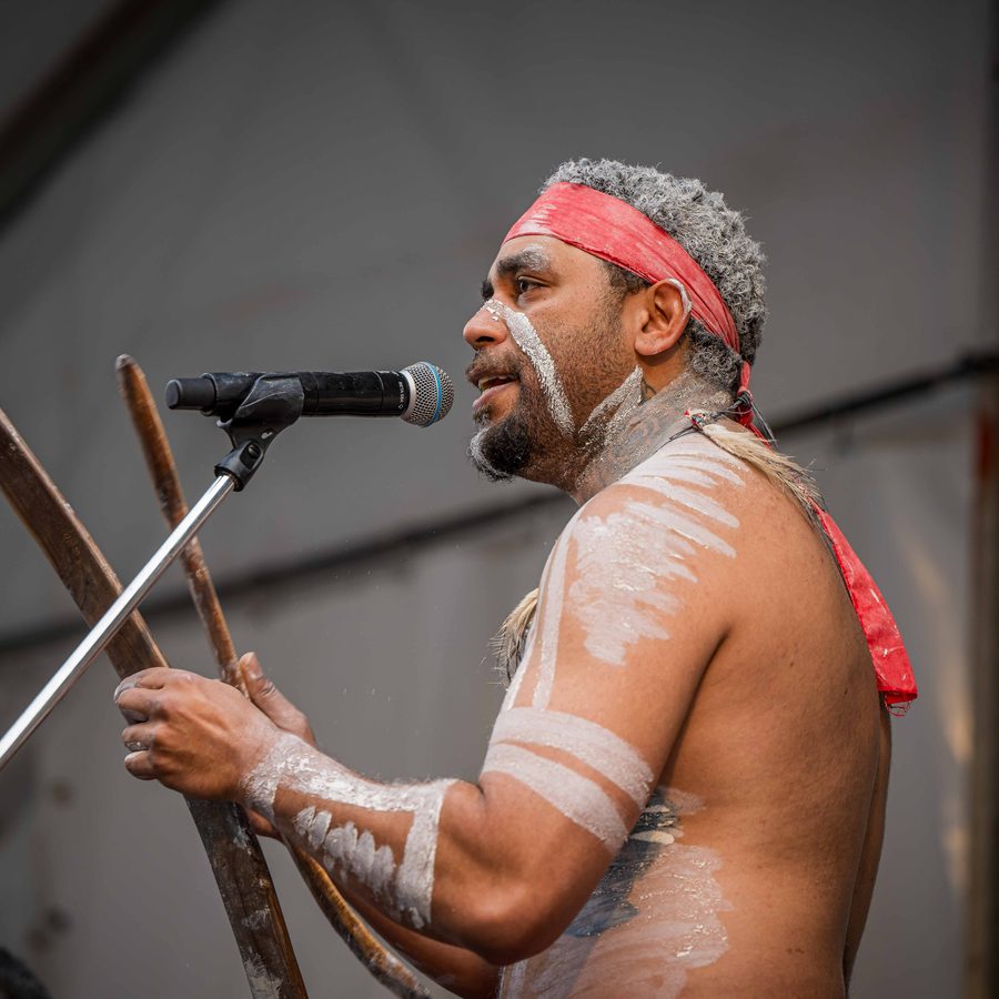 Ryka Ali at a microphone holding clapsticks