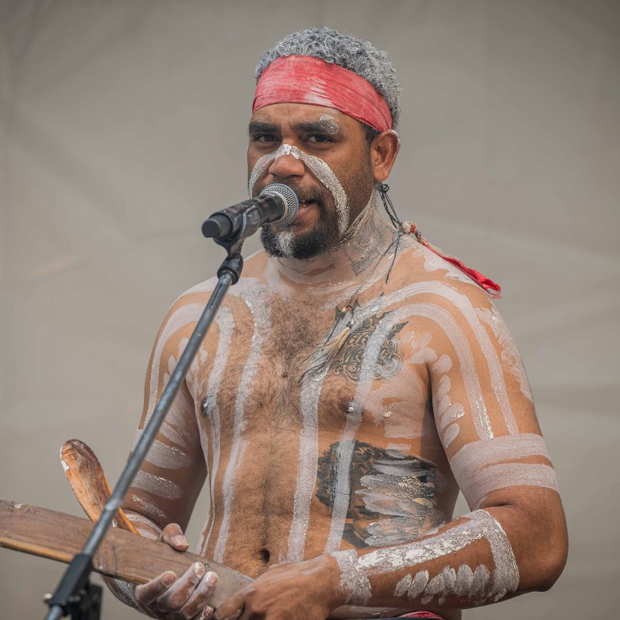 Ryka Ali speaking into a microphone during a street fair performance